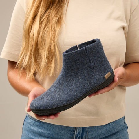 Close-up picture of a person holding a glerups boot in the color Denim blue with a black rubber sole.
